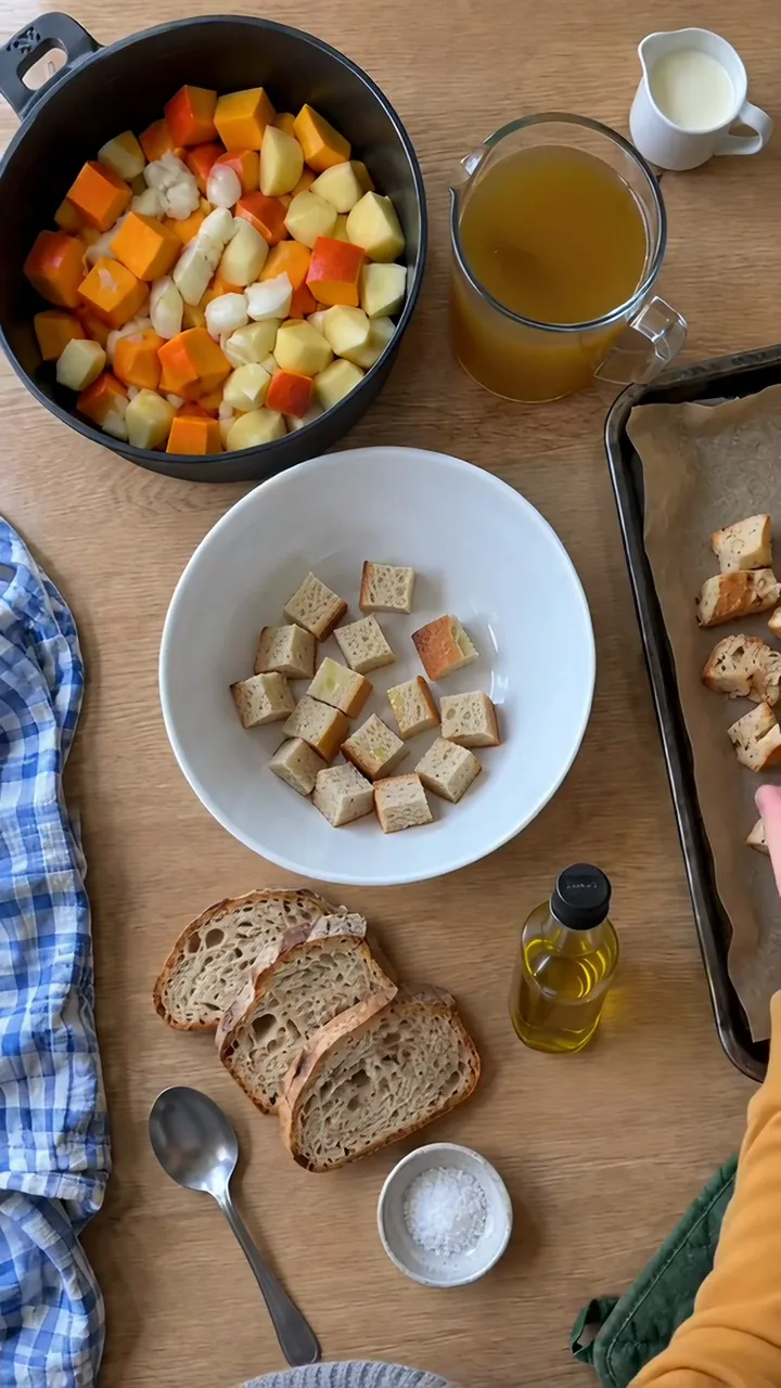 Kinderhand verteilt geölte Brotstücke auf einem mit Backpapier ausgelegten Backblech
